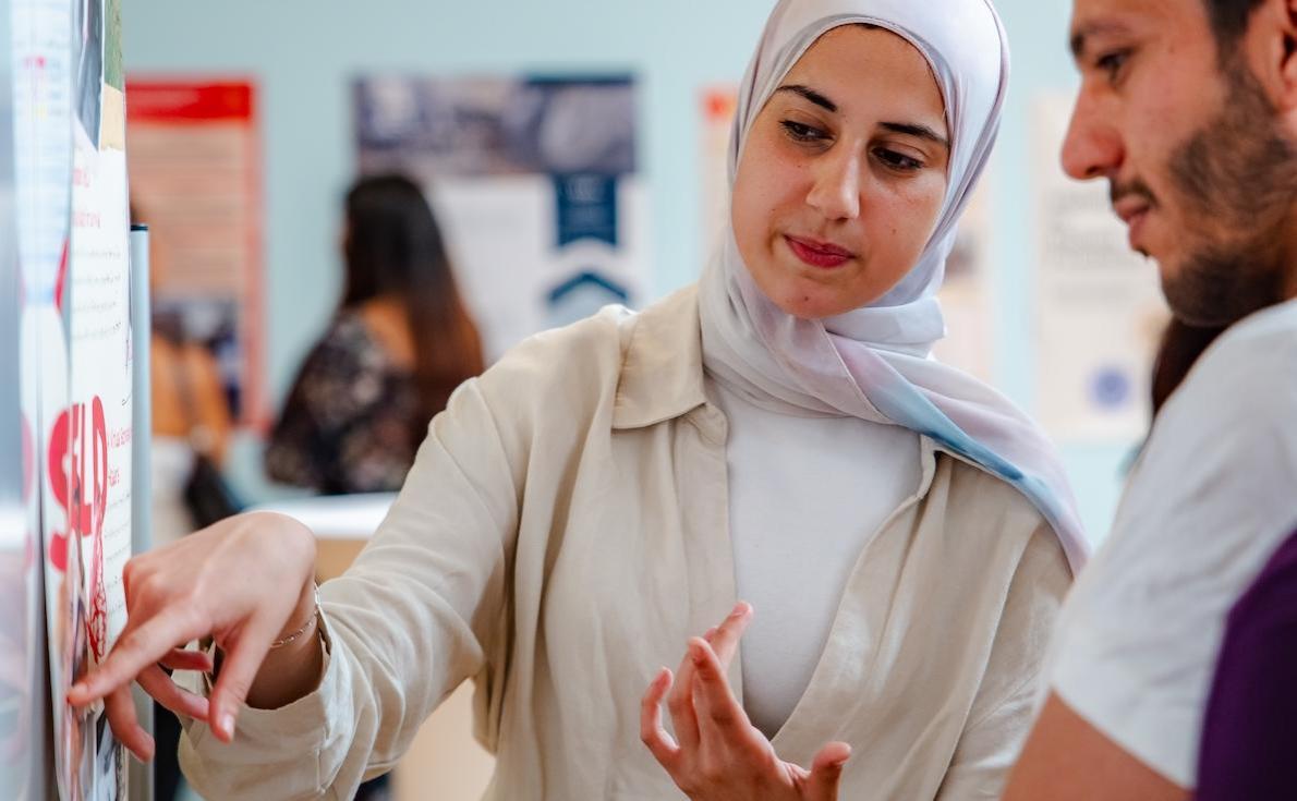 Student pointing at her poster at the Get Engaged 24 conference