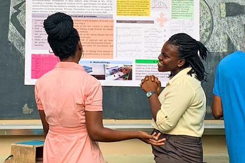 Two young women talking in front of a research poster