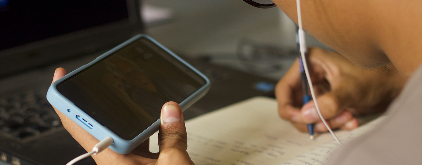 Student sudying on her laptop wearing headphones in an empty classroom