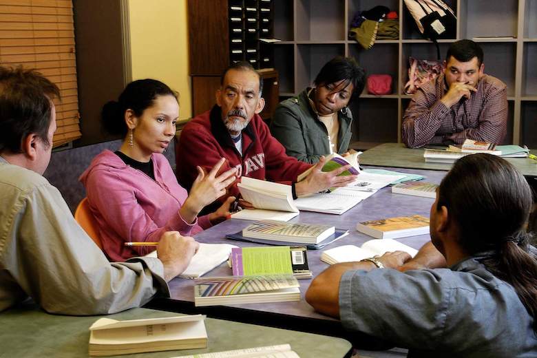People sitting around the table and a woman in the center talking
