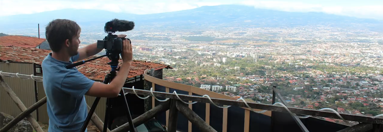 Man filming a town view from up on a hill